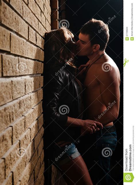 Beautiful Young Couple Kissing At Evening Near Brick Wall