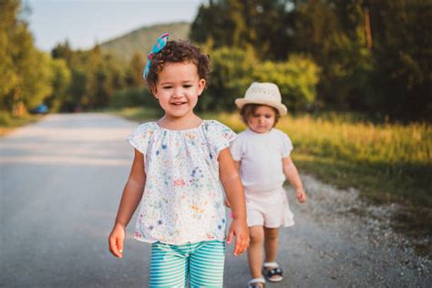 Two Sisters Walking On Path Holding Hands Smiling Stock Photos
