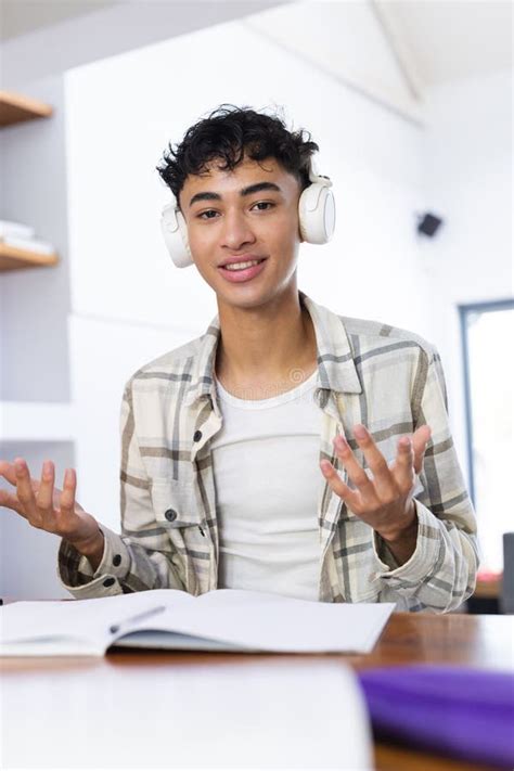 Vertical Image Of Happy Biracial Teenage Boy With Headphones Sitting At