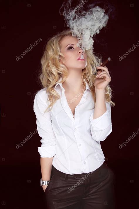 Mujer sexy con cigarro exhalando humo sobre fondo oscuro fotografía de stock VictoriaAndrea