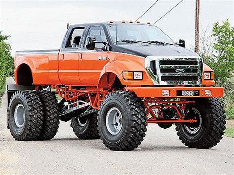 An Orange Truck With Big Tires On The Road