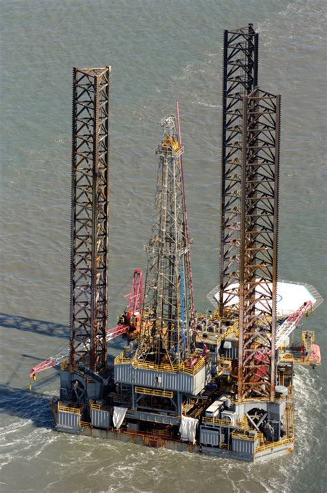 View of an oil drilling platform with a barge alongside it, and smaller boats in . Alaska Journal | Two jack-up rigs now back at work ...