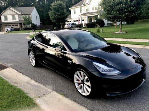 A Black Tesla Parked In Front Of A House