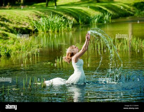 Woman Lady Walking Into Lake Water Up To Her Waist In Long Wedding Dress With Lily Pads And