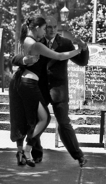 a man and woman are dancing on the street together in front of a chalkboard sign