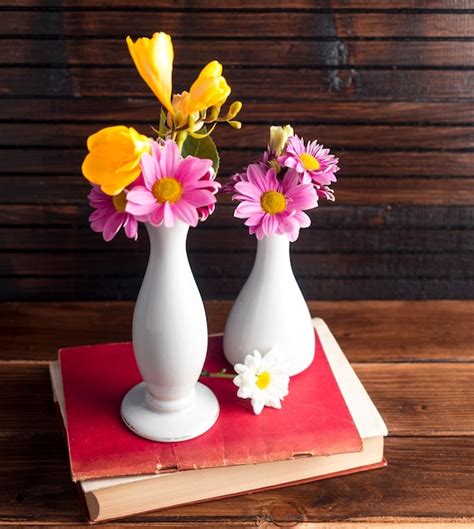 Bright Flowers In Two Vases On Book Free Photo