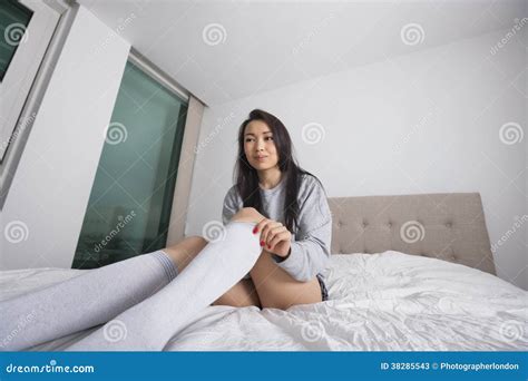 Thoughtful Young Woman Putting On Knee Socks On Bed Stock Image Image
