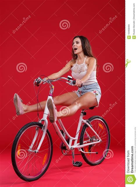 Ragazza Che Si Siede Su Una Bicicletta Che Di Sollevamento Le Sue Gambe