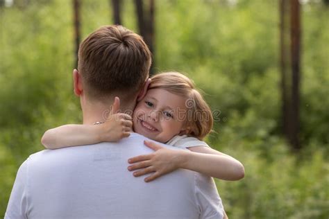 Dad And Daughter Walk In The Forest In Summer The Girl Hugs Dad By The