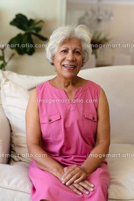 Portrait Of Smiling Biracial Mature Woman With Gray Hair Sitting On
