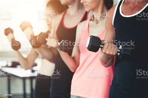 Group People In Exercise Gear Standing In A Row Holding Dumbbells