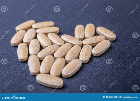 Oval Brown Pills on a Dark Blue Background in the Form of the Heart