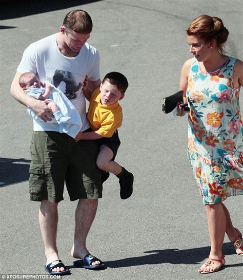 wayne rooney holds son kai under one arm and newborn klay with the other as coleen looks on