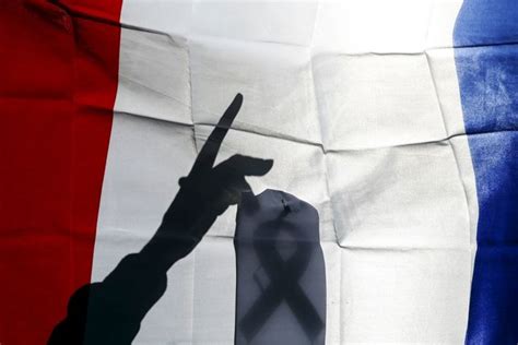 Η σημαία χωρίζεται σε δύο μέρη. Διαδηλωτής κολλά τη μαύρη κορδέλα -ένδειξη πένθους- στη ...