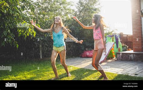 Photo Of Two Happy Laughing Sisters In Wet Clothes Dancing Under Water