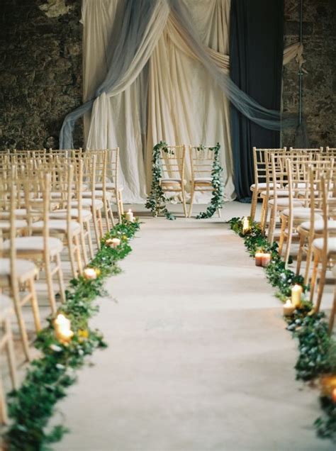 An Aisle With Candles And Greenery Is Lined Up In Front Of A Stone Wall
