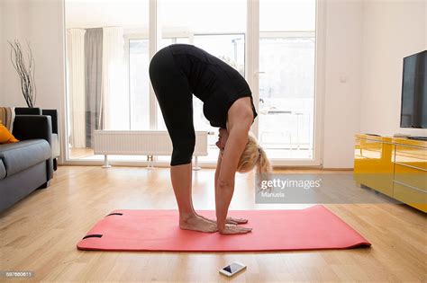 Side View Of Mature Woman In Lounge On Yoga Mat Bending Over Touching