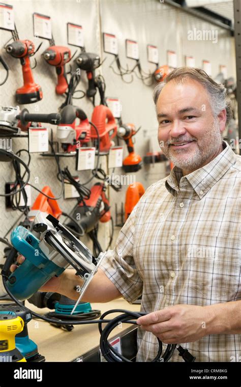 Portrait Of A Happy Hardware Store Owner With Electric Saw Stock Photo