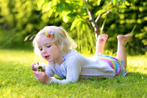 Little Kid Playing In Garden Lying In Grass Stock Photo By ©cromary