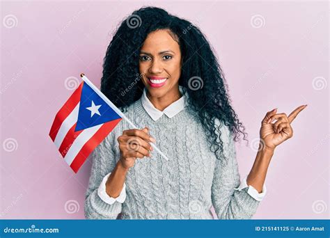 middle age african american woman holding puerto rico flag smiling happy pointing with hand and