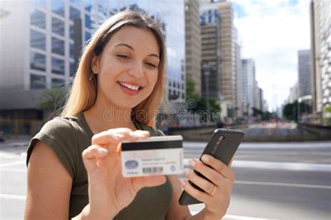 Beautiful Young Woman Watching Her Credit Card Number Using Her