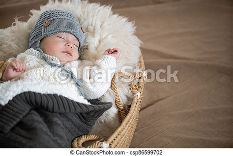 Portrait Of A Sleeping Baby In A Wicker Cradle In A Warm Knitted Hat