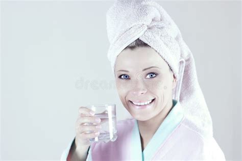 Young Woman In Robe Holding Glass Of Water Looking At Camera And