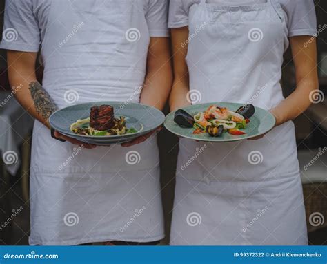 Couple Of Waiters Holding Plates Waiter And Waitress Serving Food On A Blurred Background