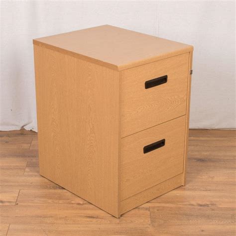 This rectangular top piece with oak veneer features two full width, stacked drawers with scoop handles and escutcheons terminating on a plinth base. Oak 2 Drawer Filing Cabinet (FC62)