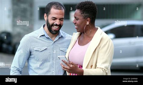 Interracial Couple Laughing In Street Holding Cellphone Candid Mixed Couple Relationship