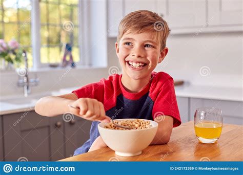 Boy At Home Eating Bowl Of Breakfast Cereal At Kitchen Counter Stock