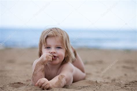 Małe dziecko dziewczynka leżeć w słońcu na plaży w pobliżu morza