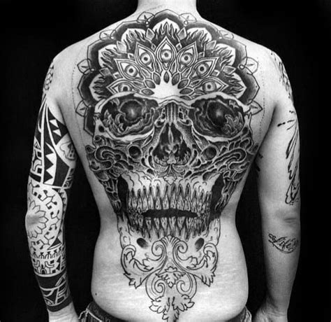 A Man With Tattoos On His Back Has A Skull And Flowers Tattoo On His Chest