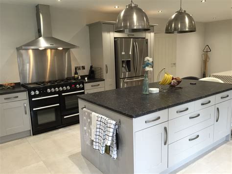 The light grey subway tiles add texture and interest to the space while the light wood floor brings warmth to the room. Grey shaker Island with leathered granite stainless steel island lights | Kitchen remodel, Grey ...