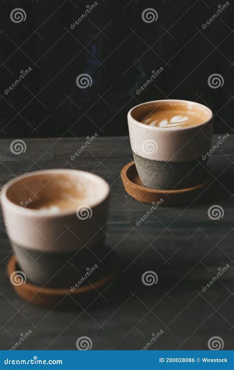 Vertical Shot Of Two Ceramic Cups Of Foamy Caffe Latte On A Wooden