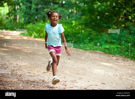Portrait Of Smiling African American Little Girl Running In Summer Park