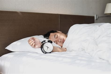 Premium Photo Asian Man Sleeping Soundly On The Bed With Alarm Clock