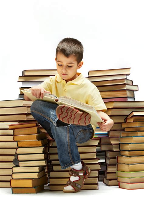 Photo Of Young Boy Reading A Book While Sitting On Books Royalty Free