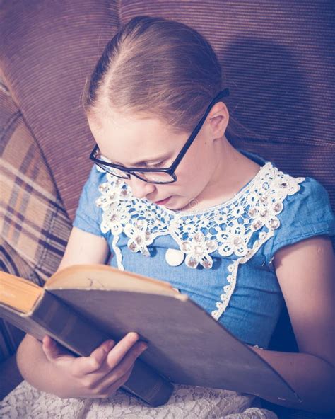 Girl Reading A Book At Home Sitting In An Armchair Stock Photo Image