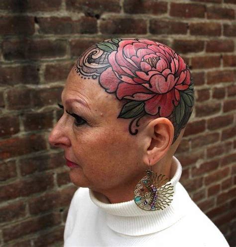 A Woman With A Flower Tattoo On Her Head Standing In Front Of A Brick Wall