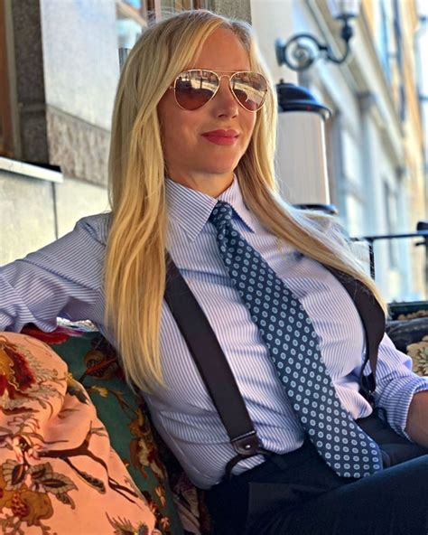 a blonde woman sitting on top of a couch wearing sunglasses and a tie with a blue shirt