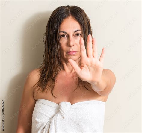 beautiful middle age woman wet hair wearing a towel with open hand doing stop sign with serious