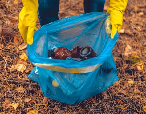 Premium Photo Female Hands In Gloves Hold A Garbage Bag With Garbage Collected In The Forest A