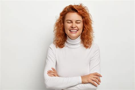 Free Photo Portrait Of Overjoyed Ginger Woman Laughs Out From Funny Joke Keeps Arms Folded