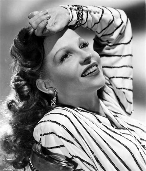 An Old Black And White Photo Of A Woman With Her Hands On Her Head Smiling