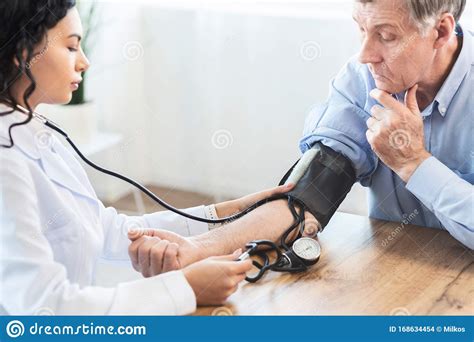 Female Nurse Checking Blood Pressure Of Mature Man Stock Photo Image