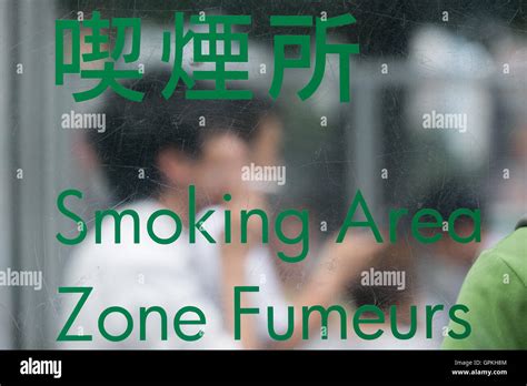 People Smoke In A Designated Smoking Area Outside Shibuya Station On