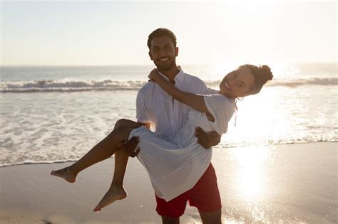 Hombre Llevando A Mujer En Sus Brazos En La Playa Foto Gratis