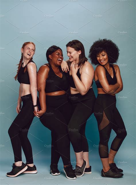four women in black sportswear posing for the camera with their arms around each other
