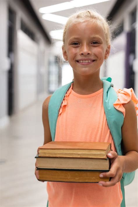Portrait Of Smiling Caucasian Elementary Schoolgirl Holding Books While